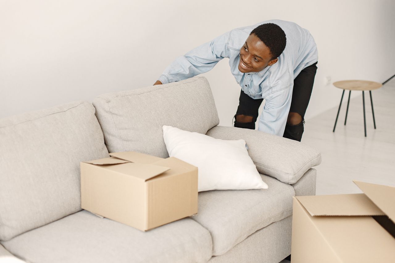about-02 Jeune homme souriant en train d’ordonner des cartons dans un salon moderne.